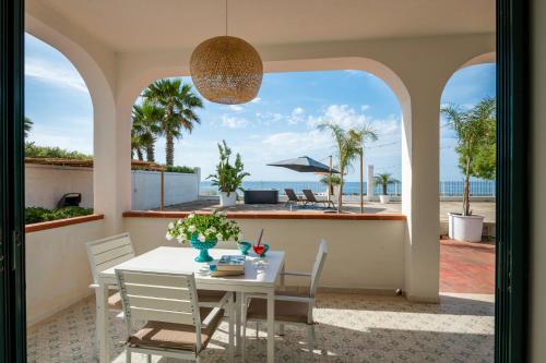 a dining room with a table and chairs and the ocean at Natoli Beach House & Villas Villa Manfredi in Molino San Biagio