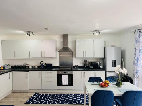 a kitchen with white cabinets and a table with blue chairs at The Barbican Apartments in Plymouth