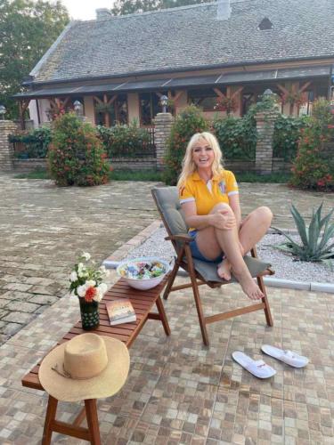 a woman sitting in a chair in front of a house at Etno kuca Kod Ognjene Milke in Novi Bečej