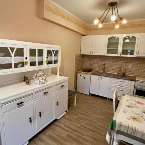 a kitchen with white cabinets and a sink and a table at Etno kuca Kod Ognjene Milke in Novi Bečej