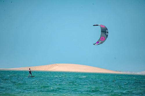 a person on a surfboard in the ocean flying a kite at White Dune Canyon in Dakhla