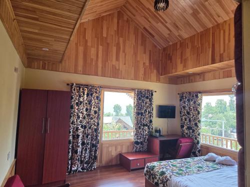 a bedroom with a bed and a desk and a window at The Pineyard Pahalgam in Kolur