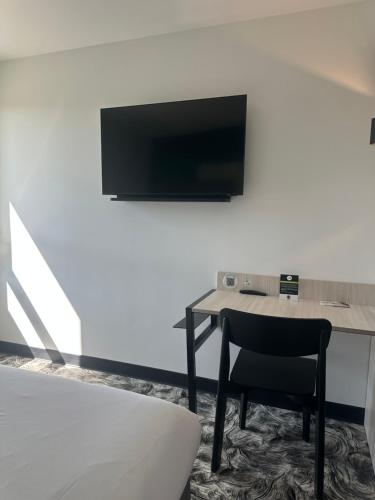 a table with a chair and a television on a wall at B&B HOTEL PERPIGNAN Nord Aéroport in Perpignan