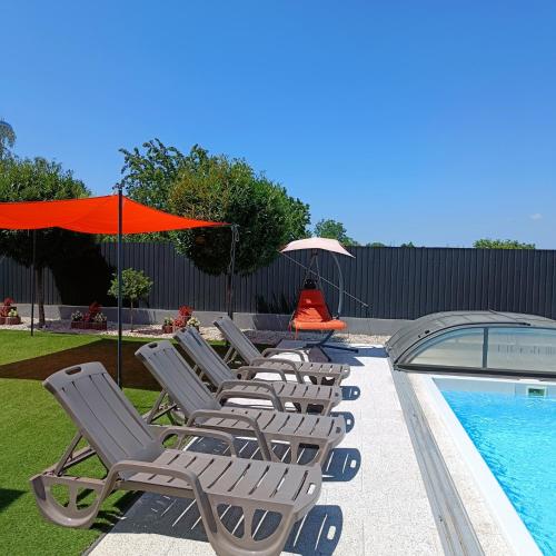 a row of chaise lounge chairs next to a swimming pool at Zöld Apartmanház in Balatonboglár
