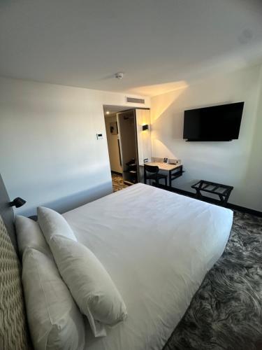 a hotel room with a bed with pillows and a television at B&B HOTEL PERPIGNAN Nord Aéroport in Perpignan