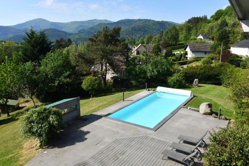 une piscine dans un jardin avec des montagnes en arrière-plan dans l'établissement LA PARENTHESE, à Saint-Amarin