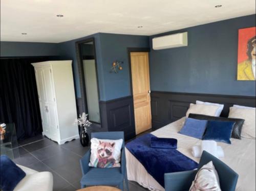a bedroom with blue walls and a bed with blue pillows at Chambre élégante avec terrasse in Souvigny
