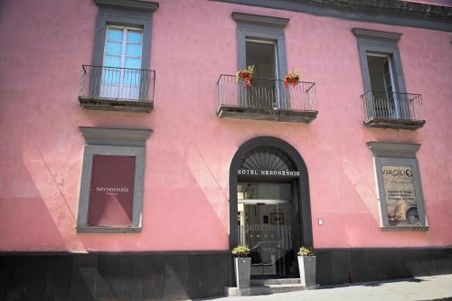 a pink building with two balconies and a window at Hotel Terme Neronensis in Pozzuoli