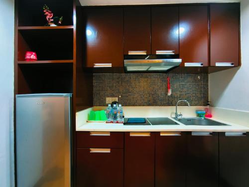 a kitchen with brown cabinets and a sink and a refrigerator at KK City Centre SCSP 3-4PAX LUXURY Family Suites NEAR IMAGO 亚庇市中心民宿 in Kota Kinabalu