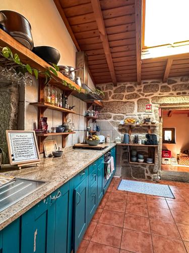 a kitchen with blue cabinets and a stone wall at Pilgrims Rest - Vila Nova de Cerveira - Hostel - Albergue - AL in Vila Nova de Cerveira