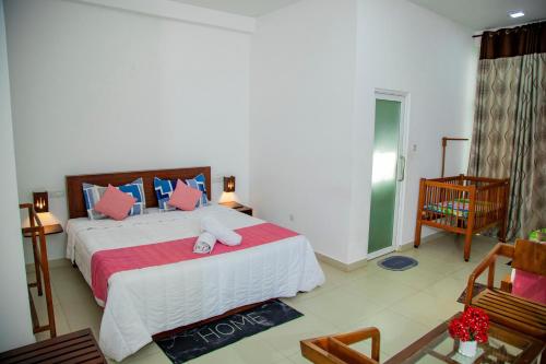 a bedroom with a large bed with pink and blue pillows at Ocean Villa Den in Galle