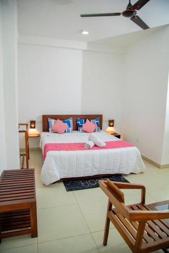 a bedroom with a large bed with pink and blue pillows at Ocean Villa Den in Galle