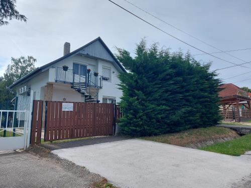 a white house with a wooden gate and a fence at Loft Apartman in Zalakaros