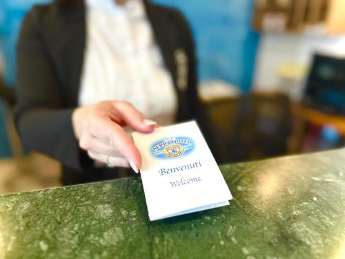 a person is holding a card on a table at Serpa Hotel in Anzio