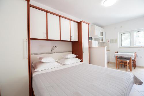 a bedroom with a large white bed and a table at Villa Alesa Steva in Tučepi