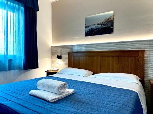 a bedroom with a blue bed with towels on it at Serpa Hotel in Anzio