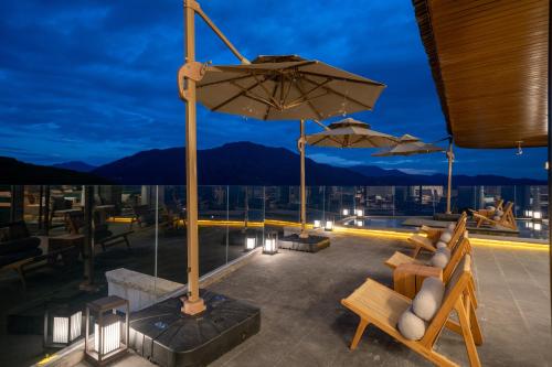 a rooftop patio with chairs and umbrellas at night at Longji Vista Retreat--Panoramic View of Terrace, Sunrise ,Heated Pool & Affordable Luxury in Longsheng