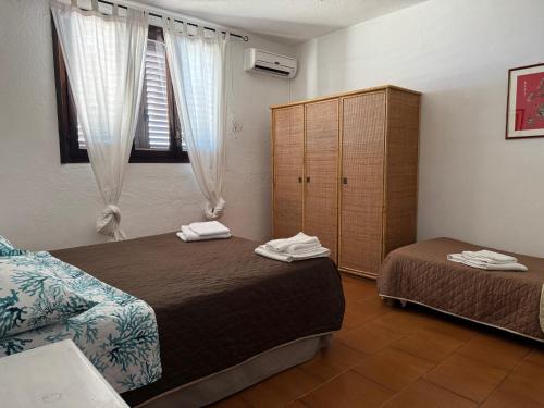 a bedroom with two beds and a cabinet and a window at Villa Francesca in Flumini di Quartu