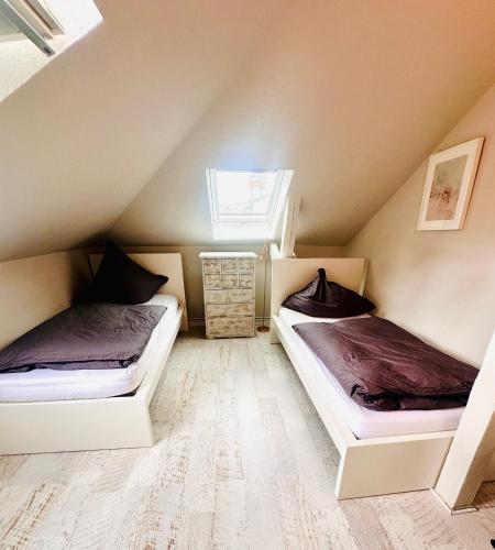 two beds in a attic bedroom with a window at Ankerplatz Neumünster, Parkplatz in Neumünster
