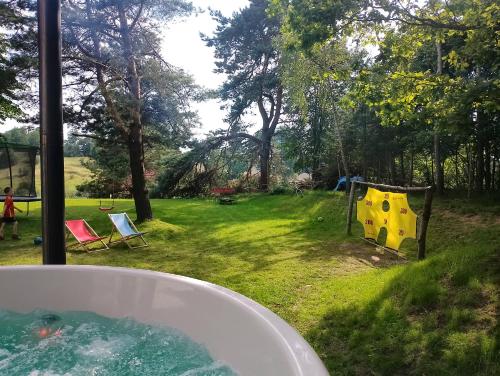 a bath tub in a yard with a playground at Warmia Forest House - Pod koronami drzew in Jedzbark