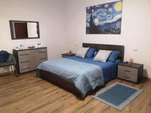 een slaapkamer met een blauw bed en een schilderij aan de muur bij Ai Quattro Ulivi in Peschiera del Garda