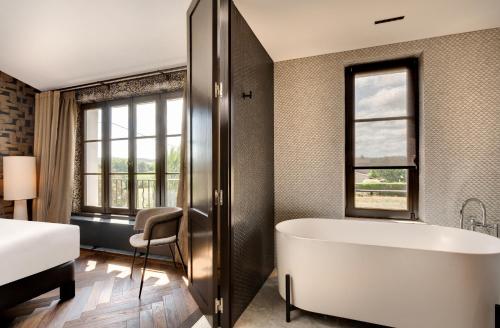 a bathroom with a large tub and a bed at La Jasso Hôtel, Maison de Famille in Carcassonne