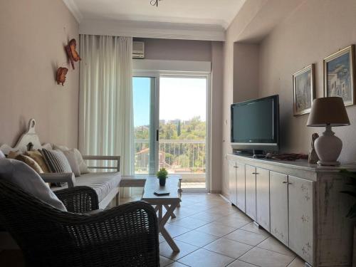 a living room with a couch and a television at Balcony By The Sea in Paleo Tsifliki