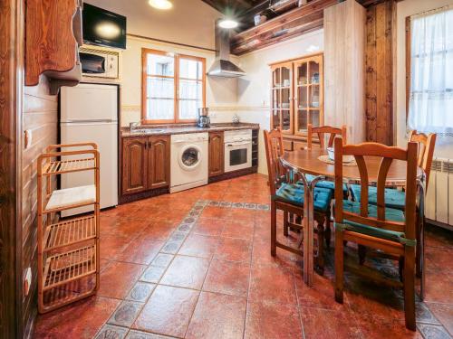 a kitchen with a table and chairs and a washing machine at Apartamentos Rurales Les Martes in Felechosa