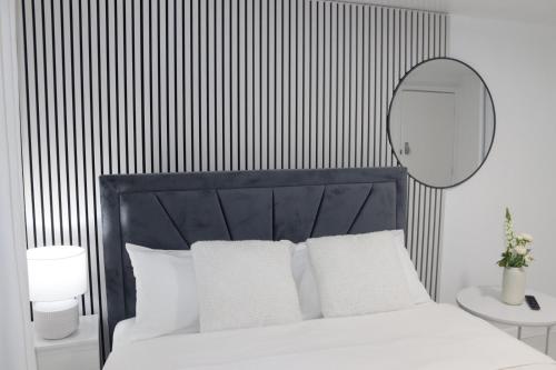 a bedroom with a white bed with a black headboard and a mirror at White Cozy Roomzzz in Oldham