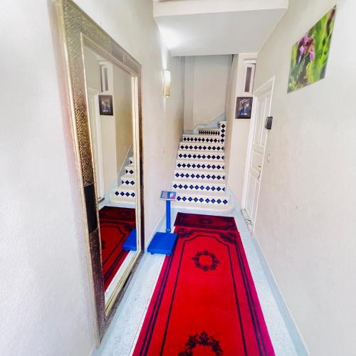 a hallway with a red carpet and stairs with a mirror at Appartement proche aeroport in Marrakech