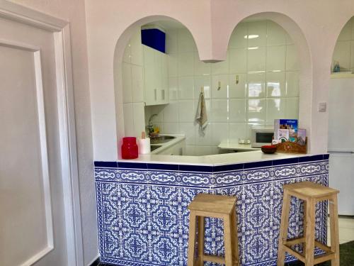 a kitchen with blue and white tiles and two stools at Good Energies Room in Málaga Center with Private Bathroom in Málaga