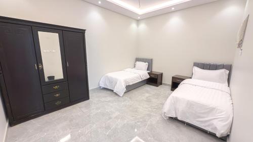 a bedroom with two beds and a dresser and a mirror at دخول ذاتي - غرفتين وصاله b in Taif