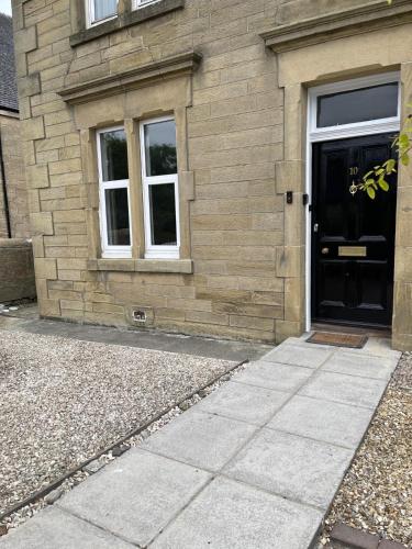 a house with a black door and a stone building at Limefield Residence in West Calder