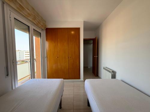 ein Schlafzimmer mit zwei Betten und einem großen Fenster in der Unterkunft Atico 3 dormitorios Sant Antoni a 400m de la playa in Sant Antoni de Calonge