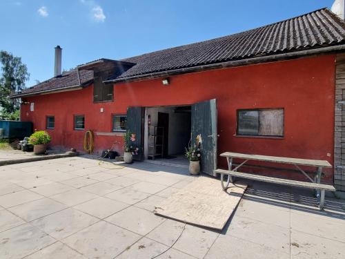 a red building with a bench in front of it at Rytterstuen - velindrettet, praktisk og perfekt til håndværkere in Helsinge
