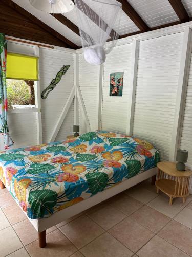 a bed with a colorful comforter in a room at Le ptit paradis créole in Sainte-Rose