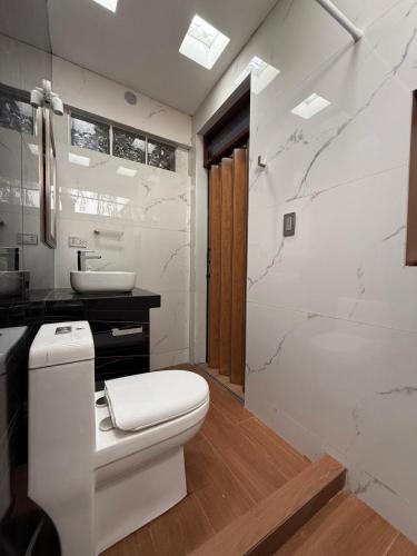 a white bathroom with a toilet and a sink at Casa los Cipreses del Sol in Cieneguilla