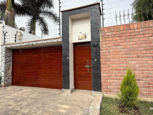 a garage with a brown door and a brick wall at Casa los Cipreses del Sol in Cieneguilla