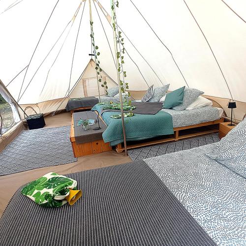 a bed in a tent with two rugs in a room at Dordogne Glamping & Camping in Bouzic