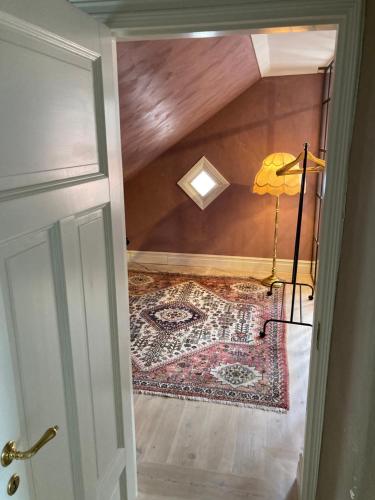 an attic room with a rug on the floor and a lamp at Rosa Huset - I hjärtat av Visby in Visby