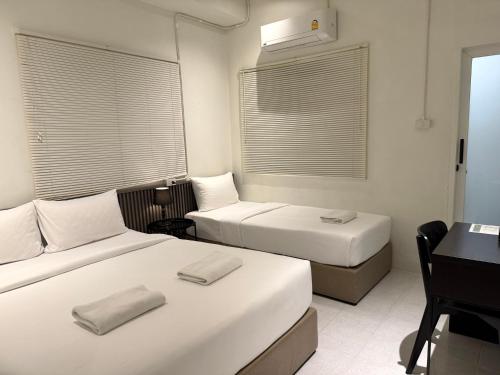 a hotel room with two beds and a desk and window at My House Guesthouse & Restaurant in Bangkok
