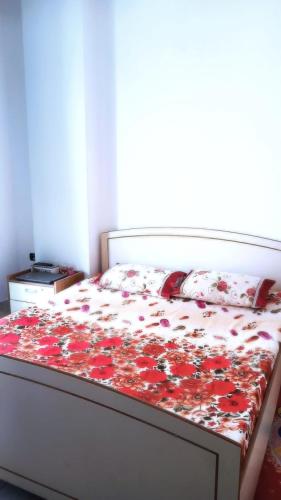 a bed in a bedroom with a bedspread with flowers at Qetesia Apartment in Shkodër