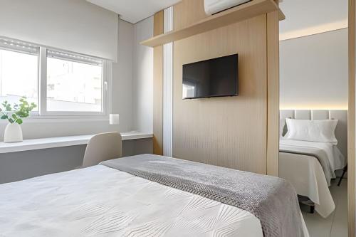 弗洛里亚诺波利斯Elegante apto Região Central Florianópolis/SC的一间卧室，墙上有一张床和一台电视