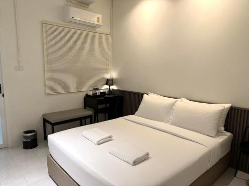 a bedroom with a bed with white sheets and a window at My House Guesthouse & Restaurant in Bangkok