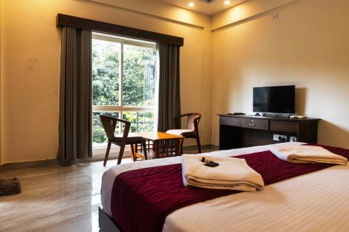 a bedroom with a bed and a table and a window at Le Eden Premium Wayanad Pool Resort in Sultan Bathery