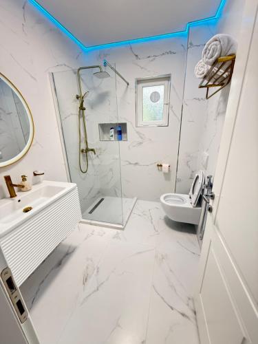 a white bathroom with a shower and a toilet at Royal Stay Apartment 1 min walk of city centre in Elbasan