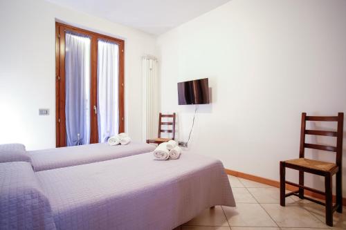 a bedroom with two beds and a tv and a chair at Casa vacanza Simona in Salionze