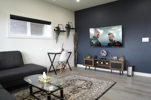 a living room with a couch and a tv on the wall at The Cozy Nook of Seton in Calgary