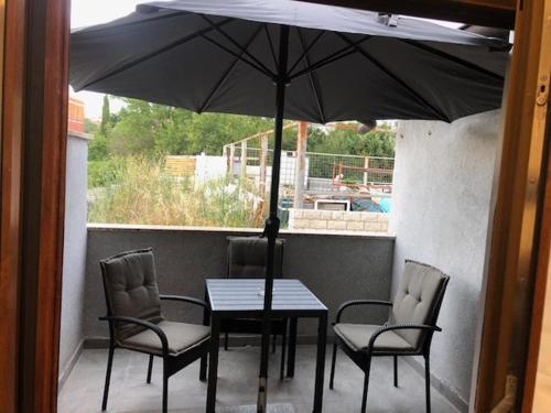a table and chairs with an umbrella on a porch at Apartment Almira in Pula