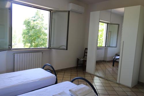 a room with two beds and a large window at Villeriunite - Villa Dalia in Baia Verde